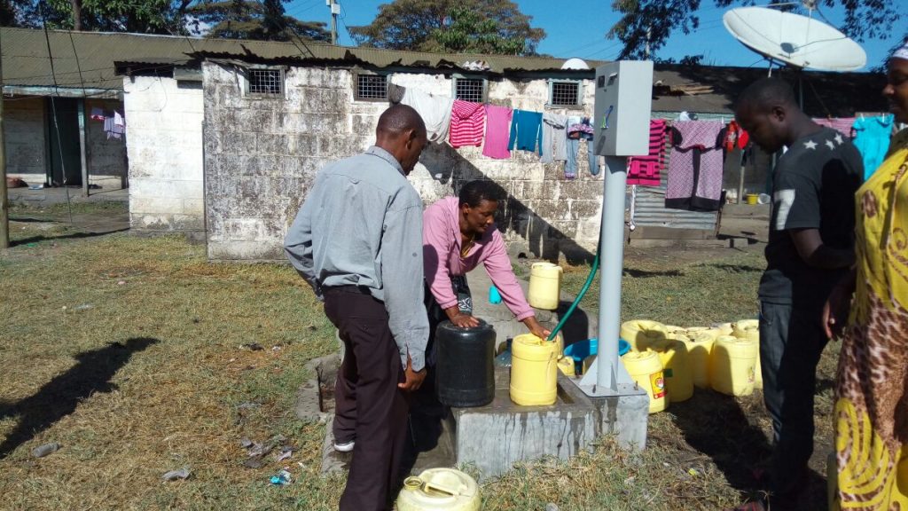 Customers using a newly pre-paid water dispenser in Nakuru